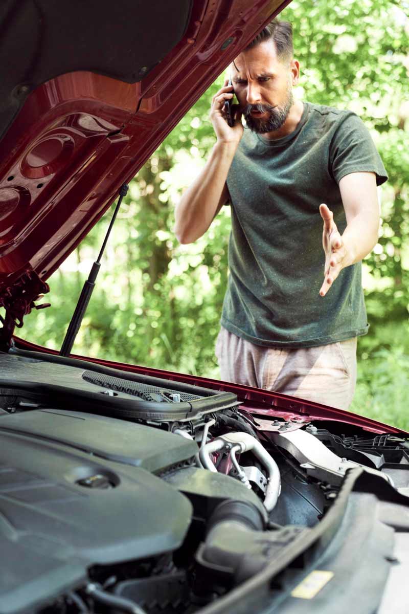 Junger Mann prüft Getriebeschaden bei Schrottauto Ankauf Overath